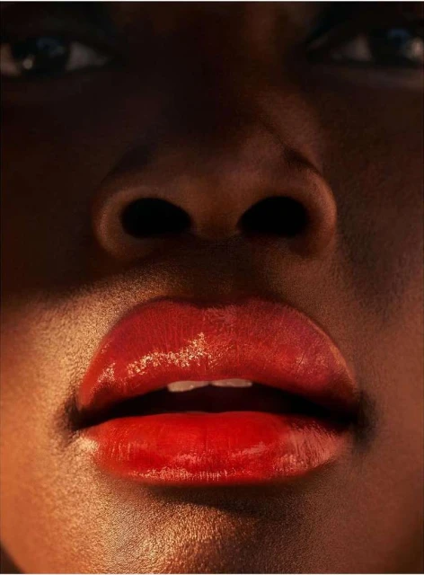 Close-up of a Black woman's face with glossy, red lips prominently displayed, emphasizing beauty and detail in skincare.