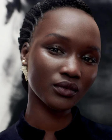 Close-up portrait of a Black woman with braided hair and star-shaped earrings directed by Thomas Slack.