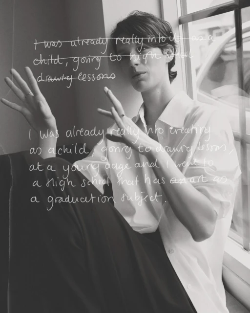 Monochrome portrait of an adult woman with short brown hair, casually posed in a white shirt near a window with superimposed text.