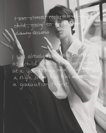 Monochrome portrait of an adult woman with short brown hair, casually posed in a white shirt near a window with superimposed text.