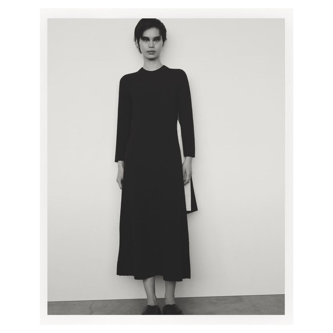 Model in black long-sleeve midi dress standing against a plain white studio background