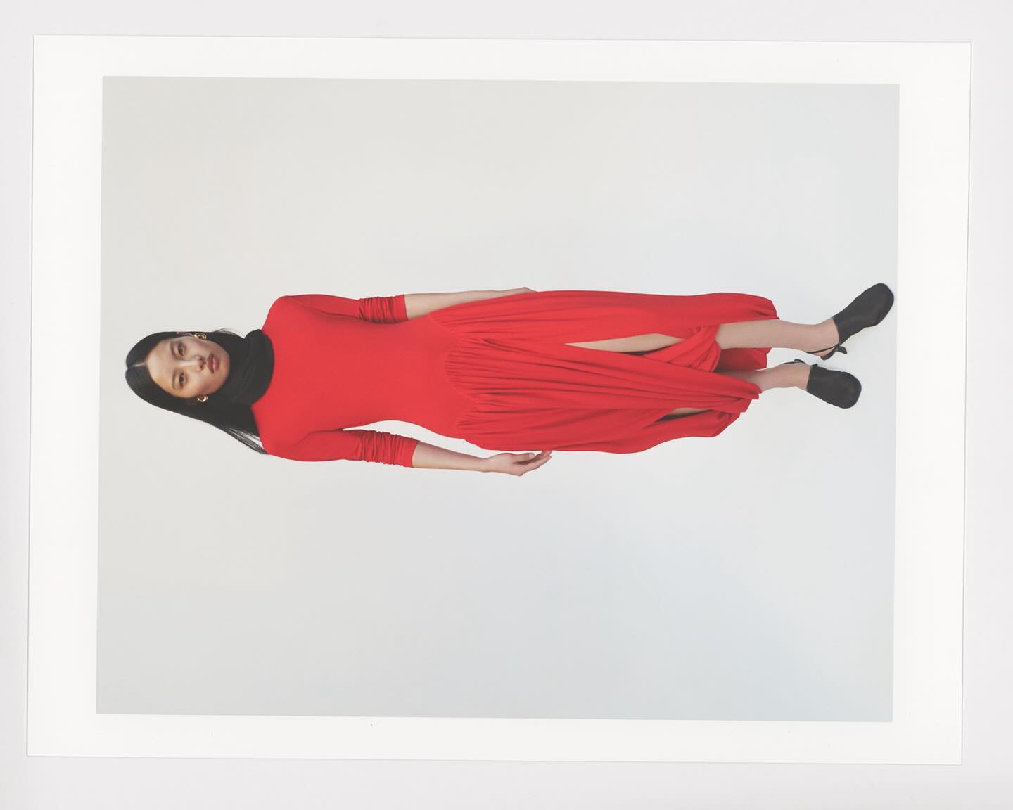 Model in long red dress with black footwear against a white studio seamless backdrop
