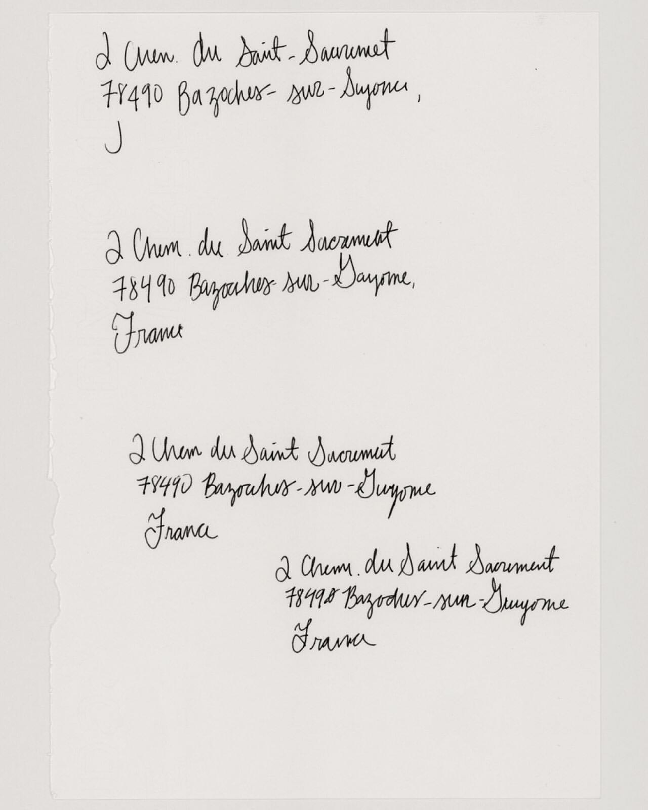 Close-up on a white sheet of paper displaying four handwritten addresses in black ink, showcasing cursive handwriting and document texture.