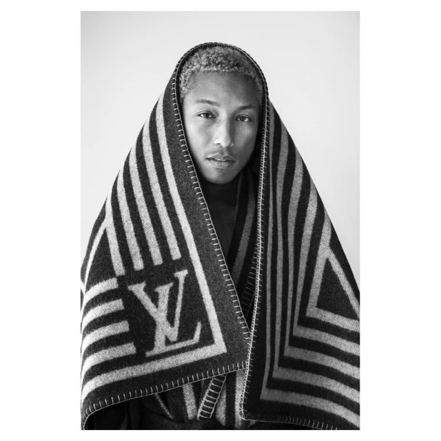 Black and white portrait of a man wrapped in a striped blanket with the 'LV' logo, showcasing his face, neck, and shoulders.