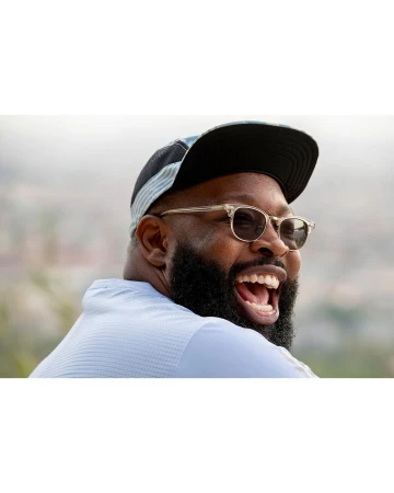Portrait of a laughing black man wearing sunglasses and a cap by photographer Tim Barber.