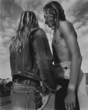 Two people with long blonde hair standing outdoors under a cloudy sky in a black and white portrait by Ward & Kweskin.