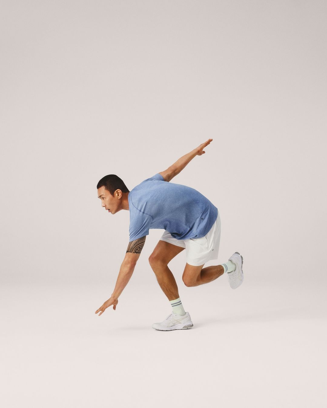 Athletic man in workout attire strikes a dynamic pose against a clean backdrop, showcasing fitness, flexibility, and modern activewear.