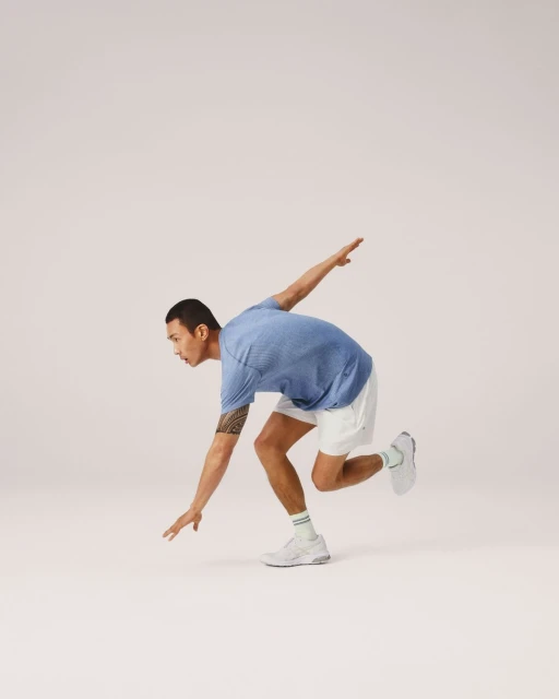 Athletic man in workout attire strikes a dynamic pose against a clean backdrop, showcasing fitness, flexibility, and modern activewear.