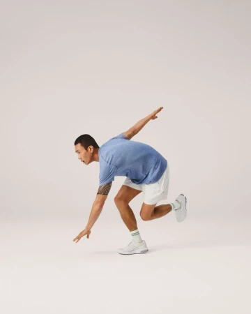 Athletic man in workout attire strikes a dynamic pose against a clean backdrop, showcasing fitness, flexibility, and modern activewear.