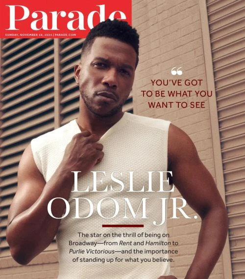Magazine cover featuring Leslie Odom Jr. in a sleeveless top, posing against a light brown wall with louvers. He is center frame.