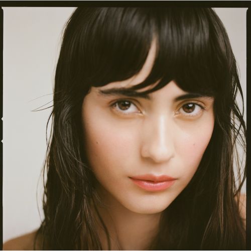 Close up portrait of a woman with dark hair and bangs against a neutral background photographed by Saloni Agarwal