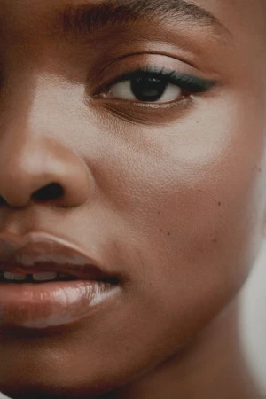 Close-up portrait of a Black woman's face highlighting winged eyeliner and glossy lips photographed by Saloni Agarwal.