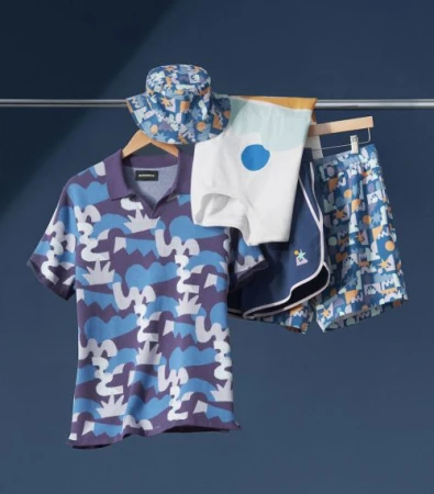 Display of a patterned polo shirt, shorts and bucket hat hanging on a metal clothing rack against a dark blue background.