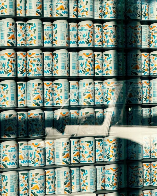 Shelves stacked with cans of flavored sparkling water featuring colorful abstract graphics on white cans in a retail setting.