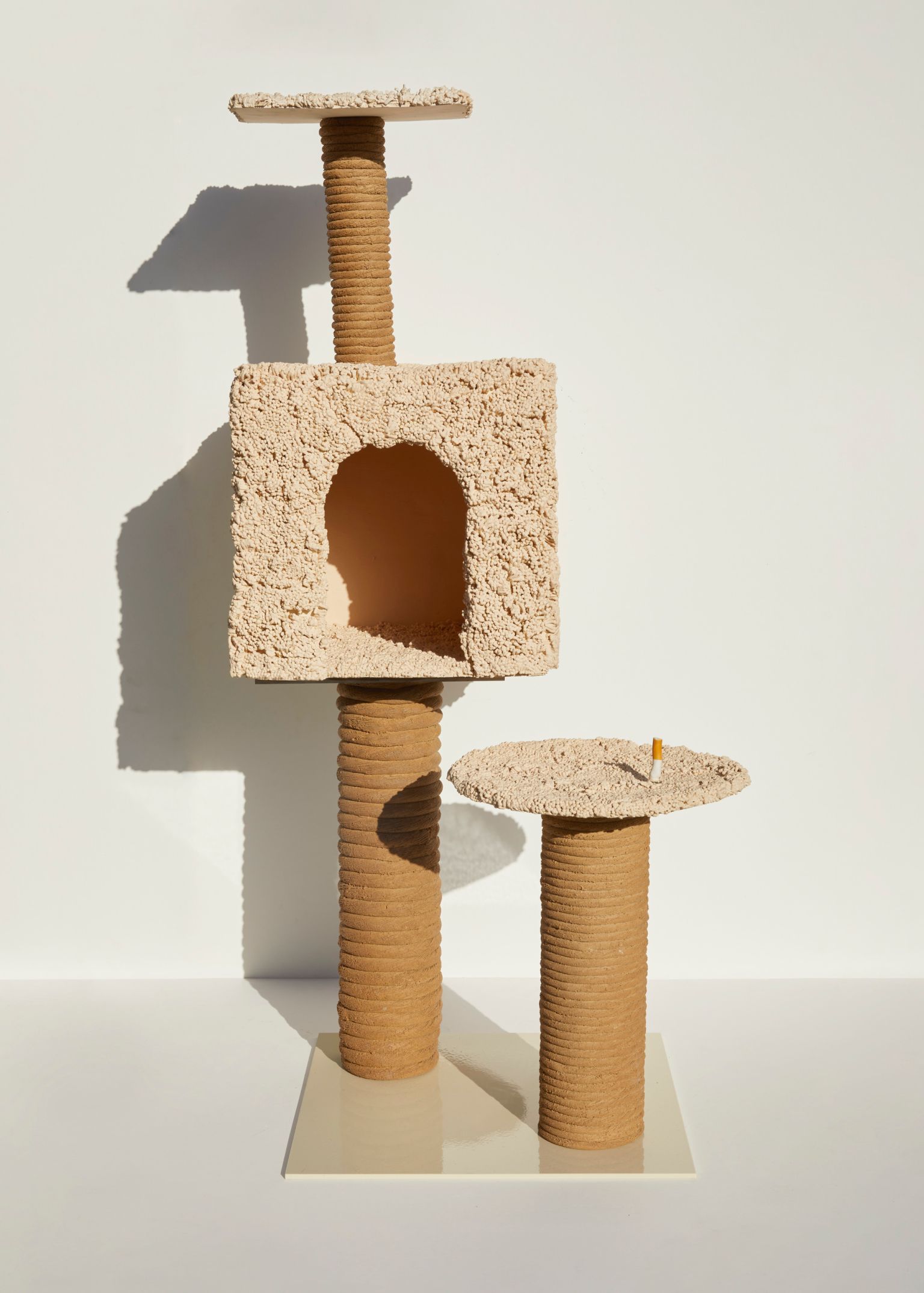 Indoor shot of a beige cat tree with multiple levels, scratching posts, and an enclosed space, set against a plain white background.