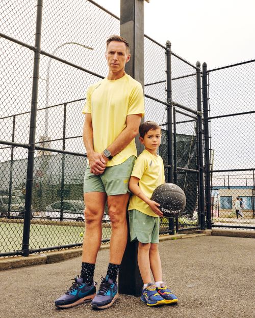 Adult male and child in matching outfits posing on an outdoor basketball court, dressed in sport attire, with a ball, sunny day.