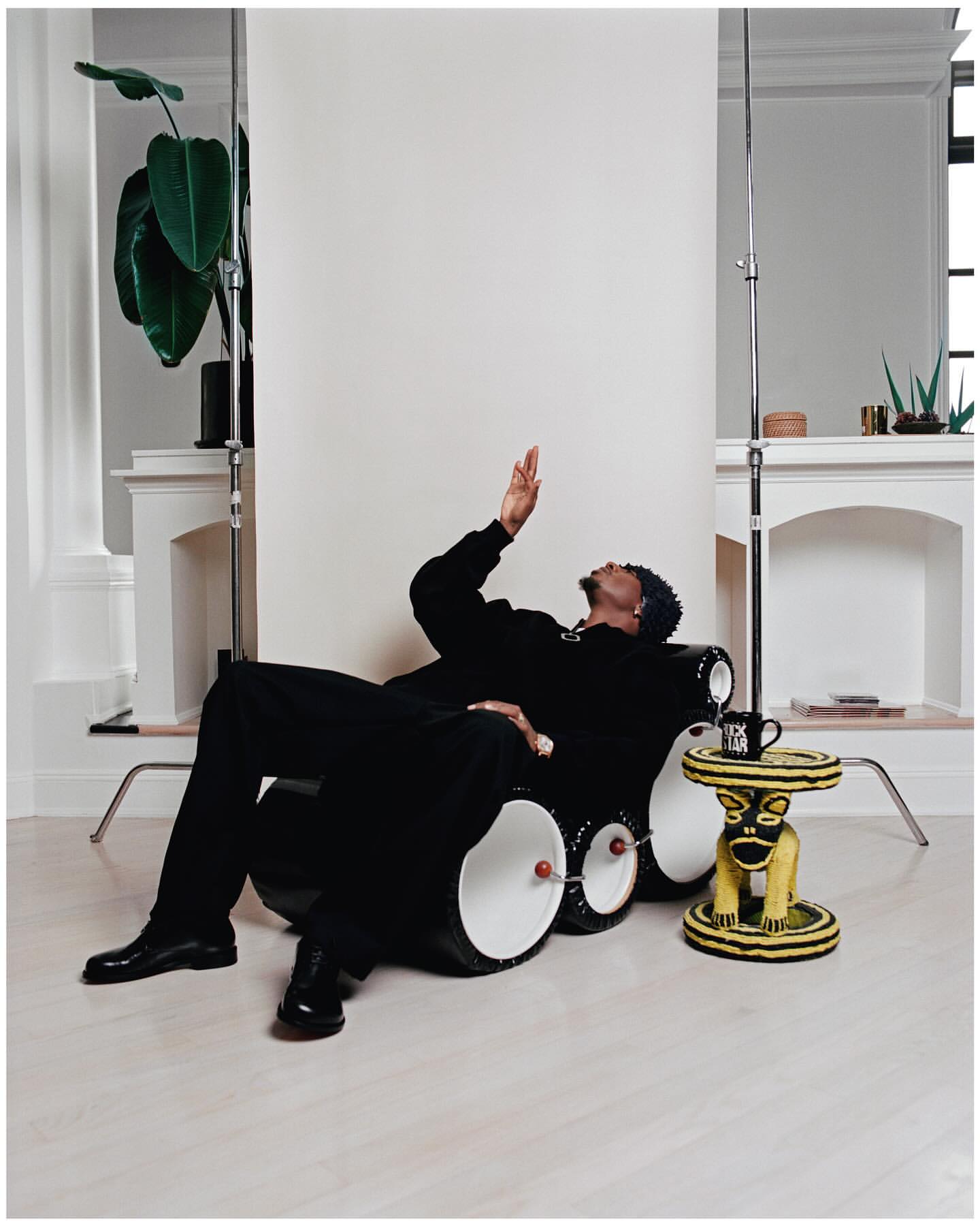 Man seated in a black sculptural chair gesturing upward in a bright interior by photographer David Cabrera