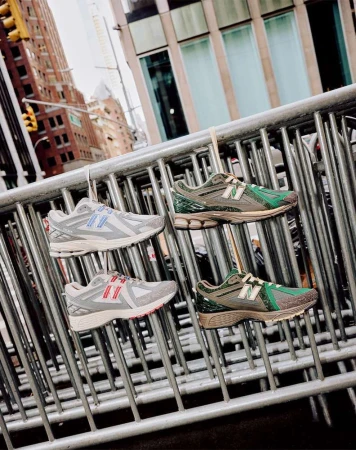 Four New Balance sneakers hang on a metal barricade against an urban backdrop, showcasing a unique product display in an outdoor setting.