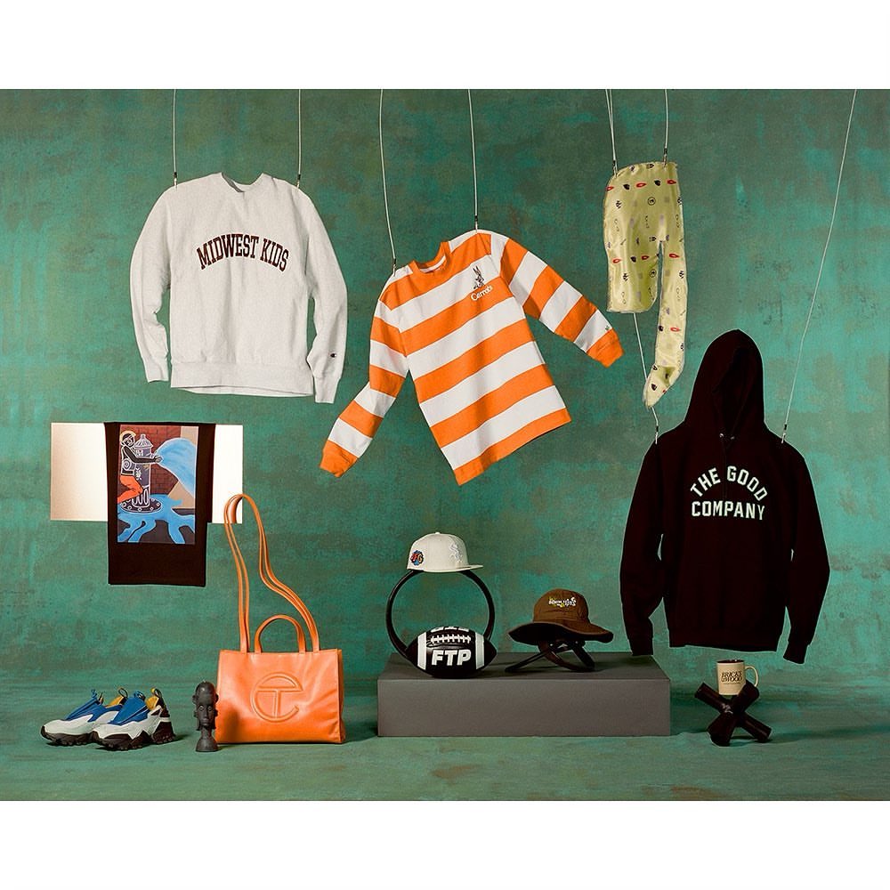 Arrangement of clothing items and accessories including sweatshirts, t-shirts, hats, shoes, a purse, and a football, suspended on strings.