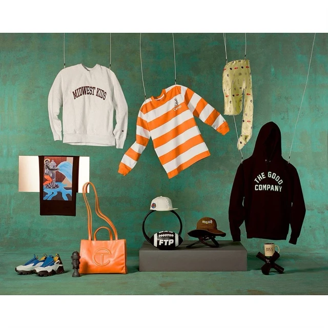 Arrangement of clothing items and accessories including sweatshirts, t-shirts, hats, shoes, a purse, and a football, suspended on strings.