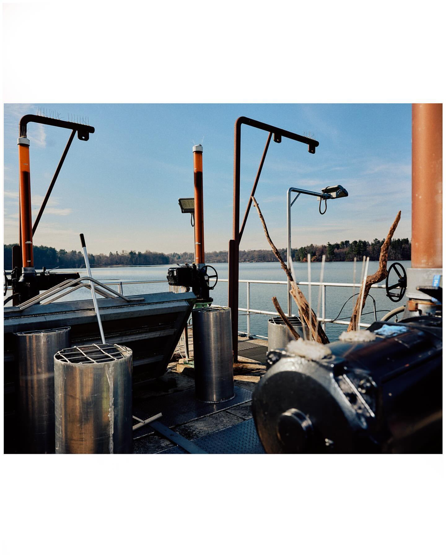 Outdoor scene featuring industrial equipment near a body of water under a blue sky, captured in a daytime shot.