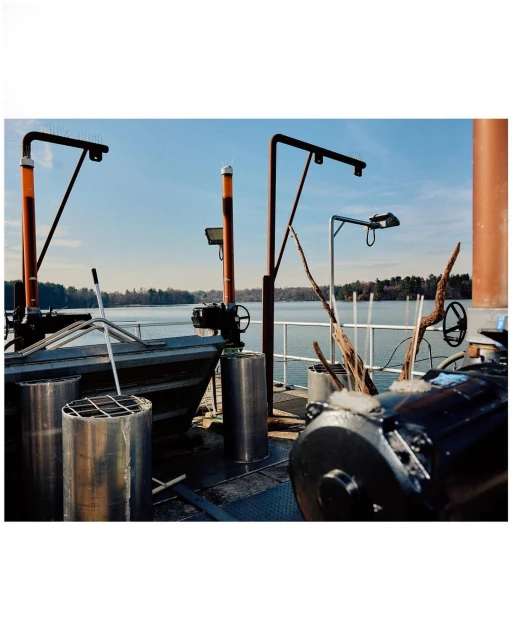 Outdoor scene featuring industrial equipment near a body of water under a blue sky, captured in a daytime shot.