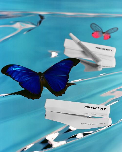 Product shot for Pure Beauty, featuring makeup with butterfly wings, set against a visually striking abstract blue background.