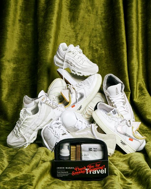 Pile of white sneakers with a sneaker cleaning kit in front of a green velvet curtain backdrop, showcasing sneaker culture.
