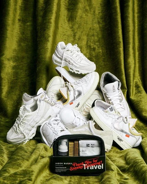 Pile of white sneakers with a sneaker cleaning kit in front of a green velvet curtain backdrop, showcasing sneaker culture.
