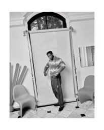 Black man in patterned sweater and loose trousers posing in studio interior by photographer David Cabrera.