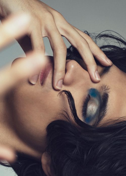 Close-up portrait of a person with dramatic blue and silver eye makeup by makeup artist Mika Curella.