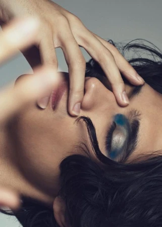 Close-up portrait of a person with dramatic blue and silver eye makeup by makeup artist Mika Curella.