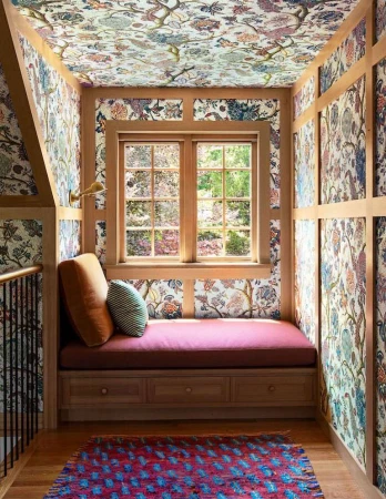 Indoor reading nook with a window seat, floral wallpaper on the walls and ceiling, hardwood floors, and natural light coming in from the window.