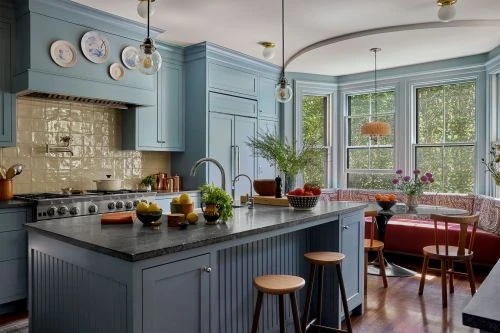 Bright, open concept kitchen with powder blue cabinets, grey countertops, wood stools, breakfast nook, and stainless steel appliances.