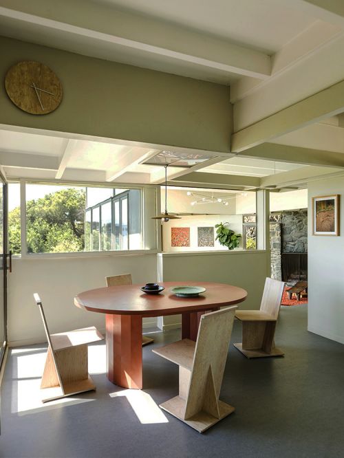 Modern wooden dining table and geometric chairs in a sunlit interior with exposed beams
