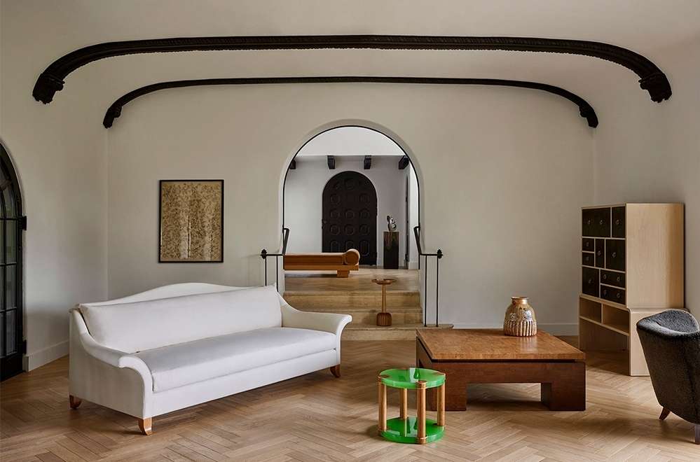 A classically styled interior room featuring a cream-colored sofa, wooden furniture, and arched doorways, creating an elegant and inviting atmosphere.