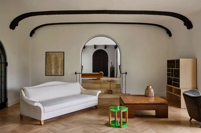 A classically styled interior room featuring a cream-colored sofa, wooden furniture, and arched doorways, creating an elegant and inviting atmosphere.