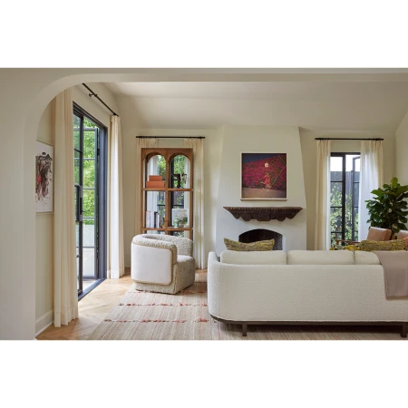 Modern living room interior with cream boucle sofa, curved armchair, fireplace, and arched glass doors by Laure Joliet.