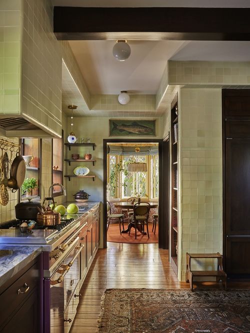 View of a residential kitchen featuring a marble countertop, range with copper accents, and a dining area visible in the background.