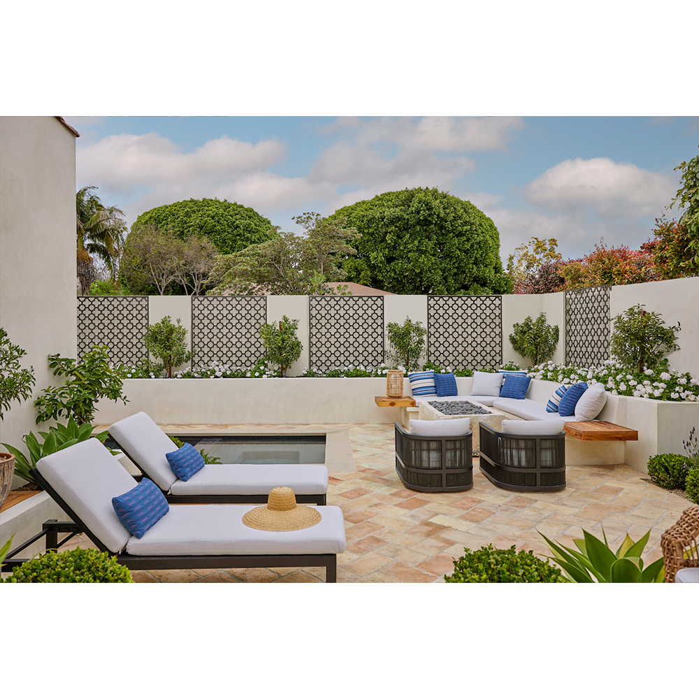 Outdoor patio with lounge chairs and seating area, featuring neutral tones, decorative lattice, plants, and a bright, sunny ambiance.