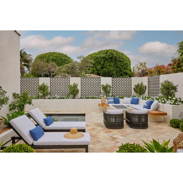 Outdoor patio with lounge chairs and seating area, featuring neutral tones, decorative lattice, plants, and a bright, sunny ambiance.
