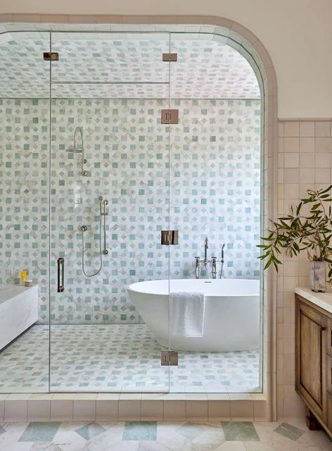 Bathroom interior with a glass-enclosed shower area featuring a white tub, tiled walls and floor, and wooden vanity cabinet.