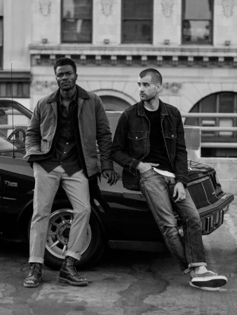 Two men posing outdoors leaning against a classic car in a black and white photograph by Nicholas Maggio
