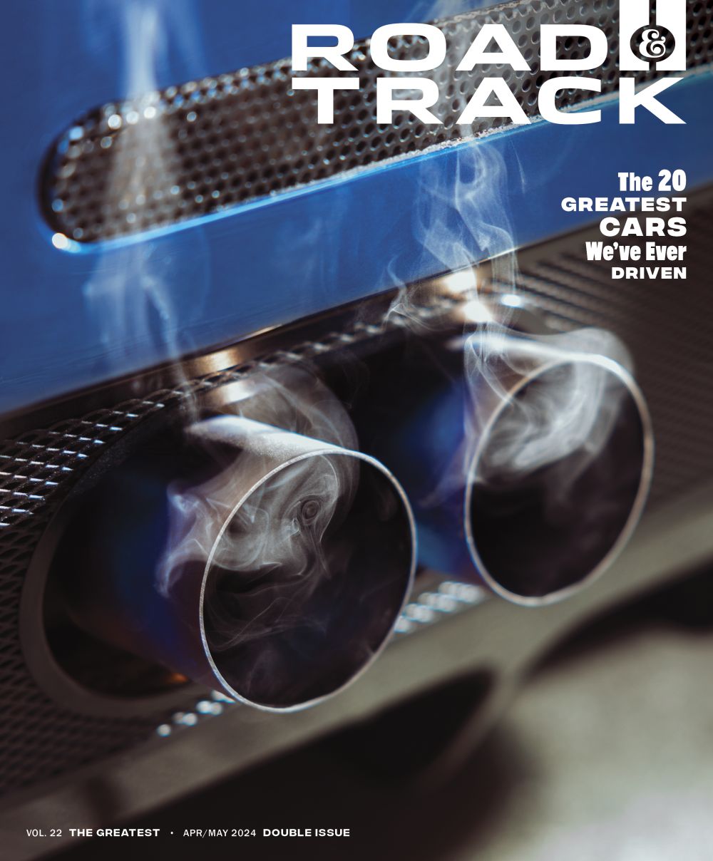 Road & Track magazine cover featuring a close-up of a car's exhaust pipes with visible smoke and a blue reflective surface.