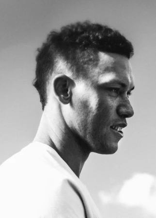 Monochrome portrait in profile of a Black man wearing a white t shirt against an outdoor sky background