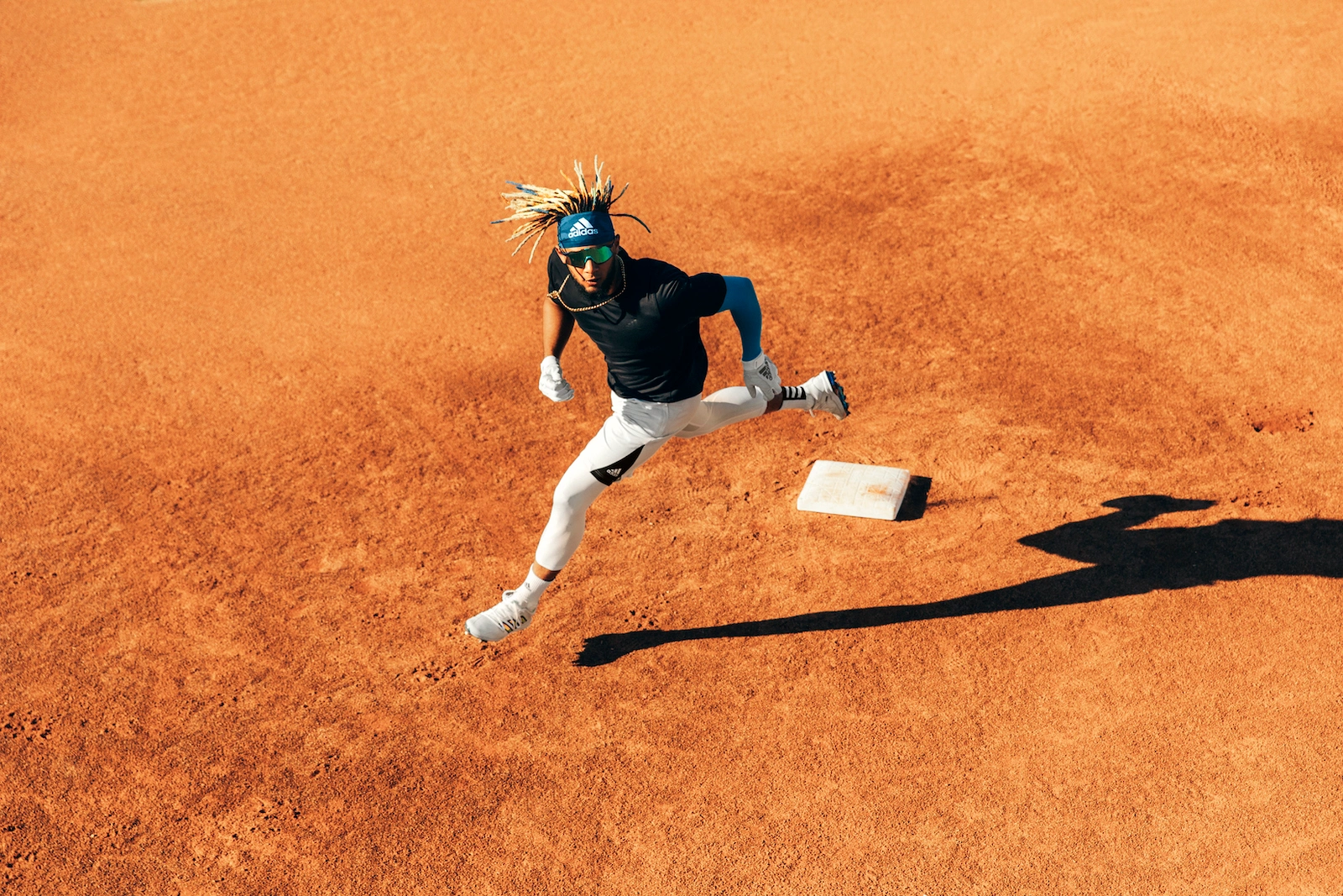 An athlete sprinting across a baseball infield past a base, captured from an elevated angle by photographer Kennett Mohrman.