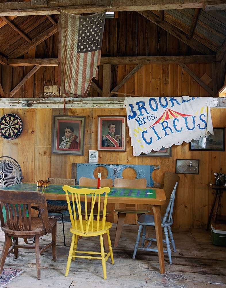 Indoor scene with a wooden table surrounded by chairs, an American flag, circus banner, and portraits on the wood-paneled wall.