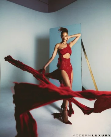 Model in a red one-shoulder cut-out dress posing as red fabric sweeps across the foreground by Fumi Nagasaka