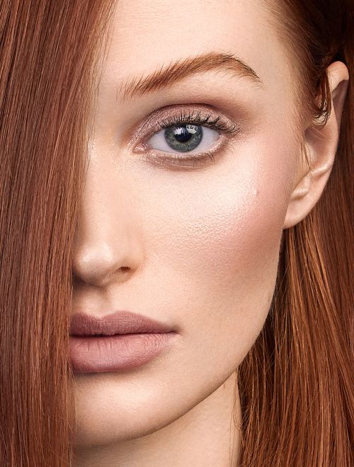 Close-up portrait of a red-haired female adult with light skin and soft makeup, focused on beauty and fashion, shot in a photo studio.