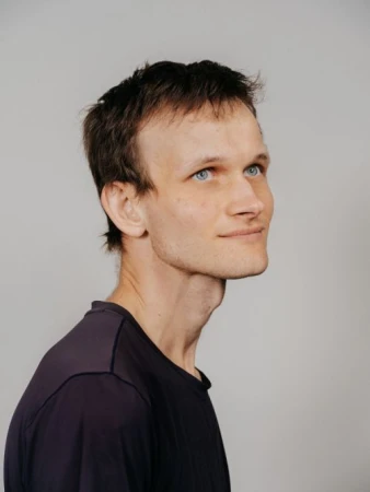 Portrait of Vitalik Buterin wearing a dark t-shirt against a plain light grey background photographed by Benjamin Rasmussen.